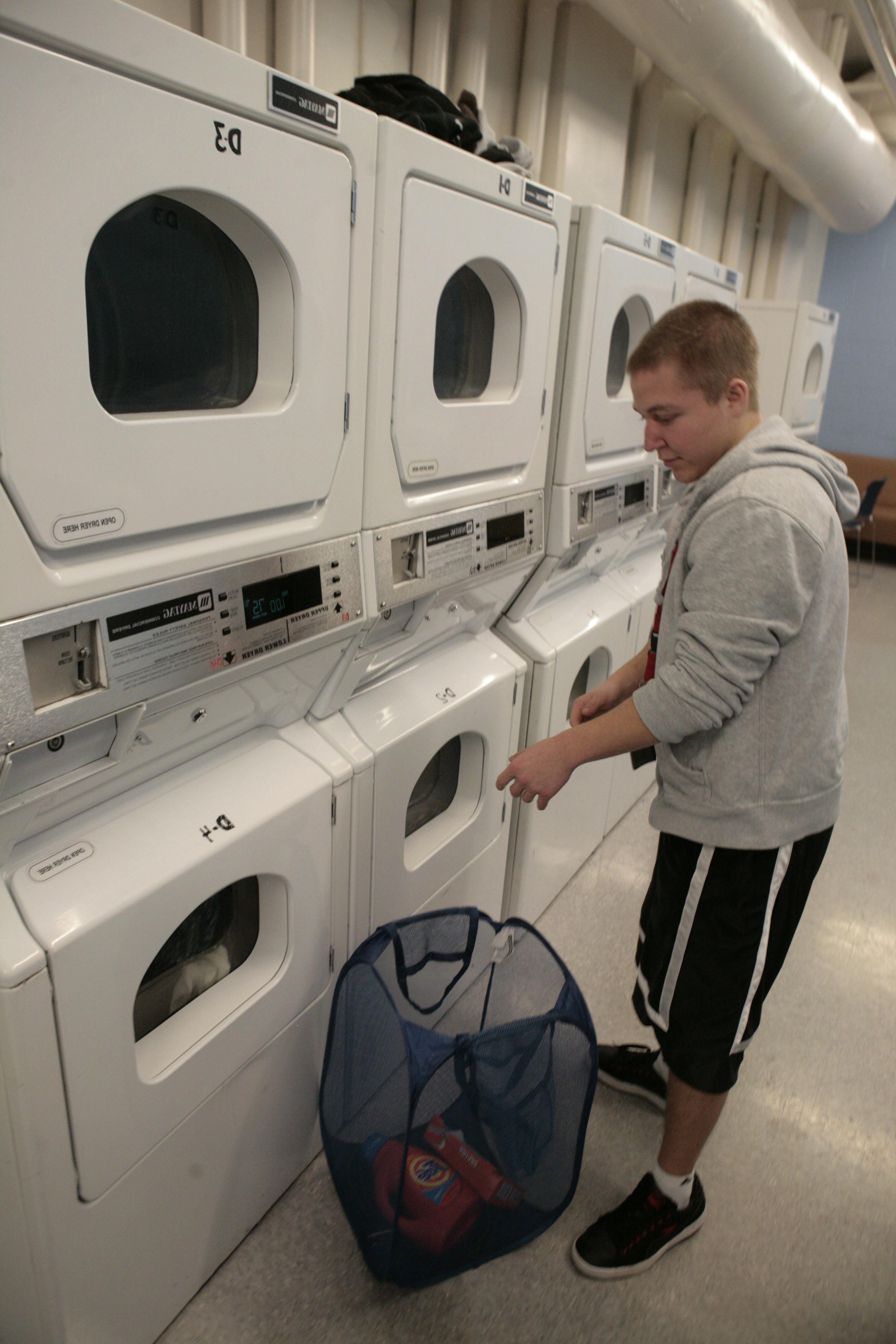 一个学生正在把要洗的衣服放进洗衣机